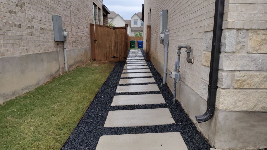 Side yard walkway finished with pavers and black gravel edging